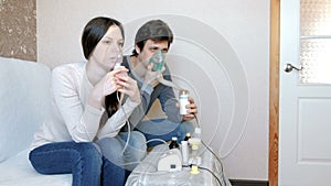Use nebulizer and inhaler for the treatment. Man and woman inhaling through inhaler mask. Front view.