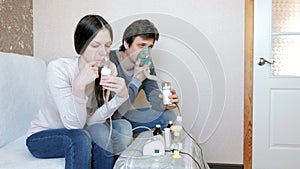 Use nebulizer and inhaler for the treatment. Man and woman inhaling through inhaler mask. Front view.