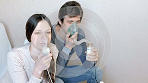 Use nebulizer and inhaler for the treatment. Man and woman inhaling through inhaler mask. Front view.