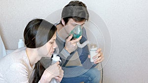 Use nebulizer and inhaler for the treatment. Man and woman inhaling through inhaler mask. Side view.