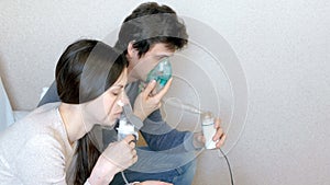 Use nebulizer and inhaler for the treatment. Man and woman inhaling through inhaler mask. Side view.