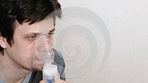 Use nebulizer and inhaler for the treatment. Young man inhaling through inhaler mask. Side view.