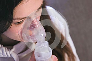 Use nebulizer and inhaler for the treatment. Young woman inhaling through inhaler mask. Close-up nose and lips in mask