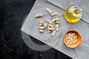 Use nut oil as cosmetics. Peanut oil in jar near peanut in bowl on blue tablecloth on black background top view copy