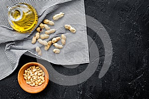 Use nut oil as cosmetics. Peanut oil in jar near peanut in bowl on blue tablecloth on black background top view copy