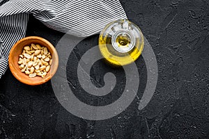 Use nut oil as cosmetics. Peanut oil in jar near peanut in bowl on black background top view copy space