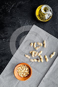 Use nut oil as cosmetics. Peanut oil in jar near peanut in bowl on blue tablecloth on black background top view copy