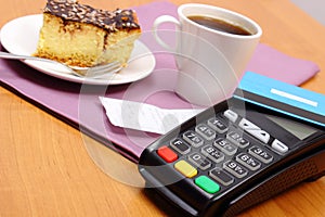 Use payment terminal for paying for cheesecake and coffee in cafe, finance concept