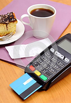 Use payment terminal for paying for cheesecake and coffee in cafe, finance concept