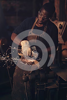 Use a power tool for a power finish. a young man using an angle grinder while working at a foundry.