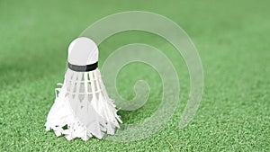 A used badminton shuttlecock on green grass