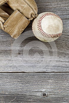 Used baseball and weathered mitt on old wood