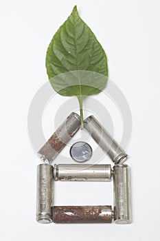 The used batteries lie in the form of a house. Above them is a juicy green leaf.