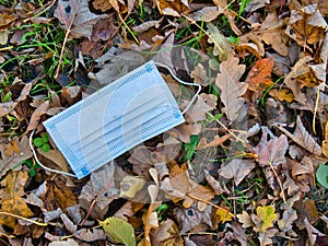 A used, blue surgical mask used for COVID-19 PPE protection, discarded as litter in a rural area