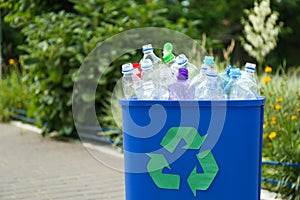 Used bottles in trash bin outdoors, space for text. Plastic recycling