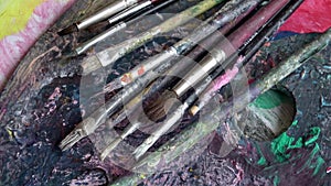 Used brushes on an artist\'s palette of colorful oil paint