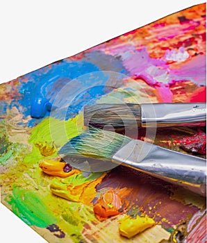 Used brushes on an artist's palette of colorful oil paint