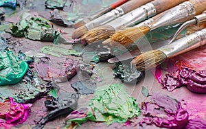 used brushes in an artist's palette of colorful oil paint for dr