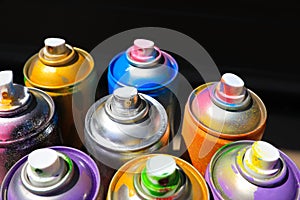 Used cans of spray paint on dark background, closeup. Graffiti supplies