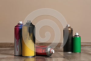 Used cans of spray paint on floor indoors.