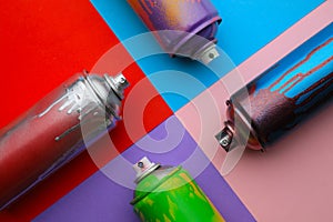 Used cans of spray paints on color background, flat lay. Graffiti supplies