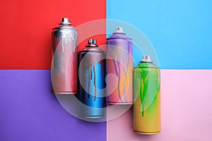 Used cans of spray paints on color background, flat lay. Graffiti supplies