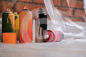 Used cans of spray paints on floor indoors. Graffiti supplies