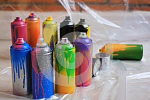 Used cans of spray paints on floor indoors. Graffiti supplies