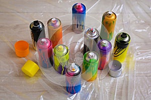 Used cans of spray paints on floor indoors. Graffiti supplies