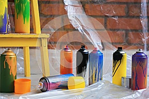 Used cans of spray paints near brick wall indoors. Graffiti supplies