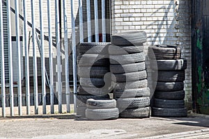 Used car tyres or tires stacked on top of each other outside a car garage or workshop