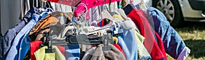 Used child and baby clothes displayed on rack for exchange