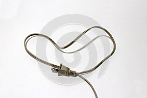 Used cream color of plug with cable put like a heart on the white floor, love concept of electrician.