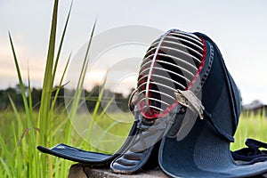 Used and Dirty Kendo Helmet or Men in grass field on sunset background.