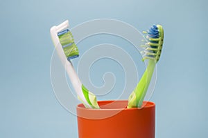 Used dirty and new toothbrush bristles in a plastic glass. Hygiene concept photo.