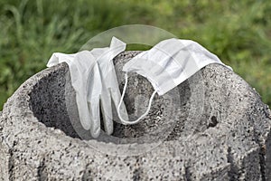 Used disposable glove and face mask on a garbage container close up.