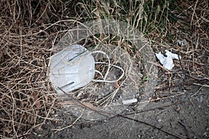 Used face mask, disposable, thrown out on the ground in the environment as garbage during the corovavirus covid 19 crisis.