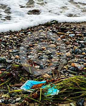 Used face mask washed ashore polluting the beach.