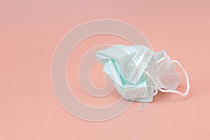 Used green medical face mask was crumpled on old rose background. The concept of rejection or disposal mask after quarantine