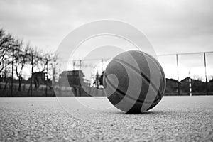 Used leather basketball on grey asphalt background.