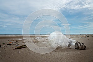 Used light bulb and garbage on the beach