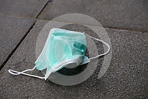 Used medical face mask discard on pavement floor