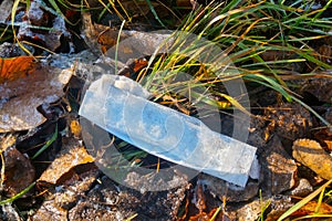 A used medical mask lies on the fallen frostbitten foliage. Coronavirus protection. The concept of fighting and ending