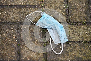 Used medical mask on street ground