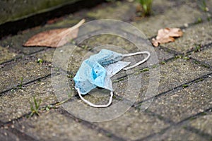 Used medical mask on street ground