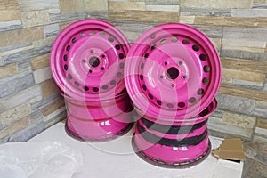 Used Metal stamped rims for cars. Custom made pink steel wheels on the stone wall background