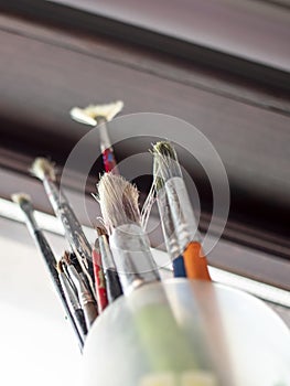 Used oil paint brushes illuminated by daylight filtering through the window. close up.