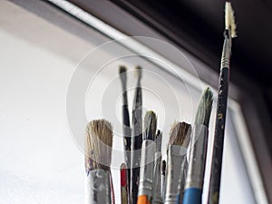 Used oil paint brushes illuminated by daylight filtering through the window. close up.