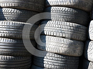 Used, old tires stacked one on another next to shop garage