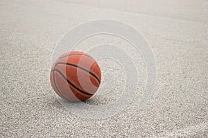 Used orange leather basketball on grey asphalt background.